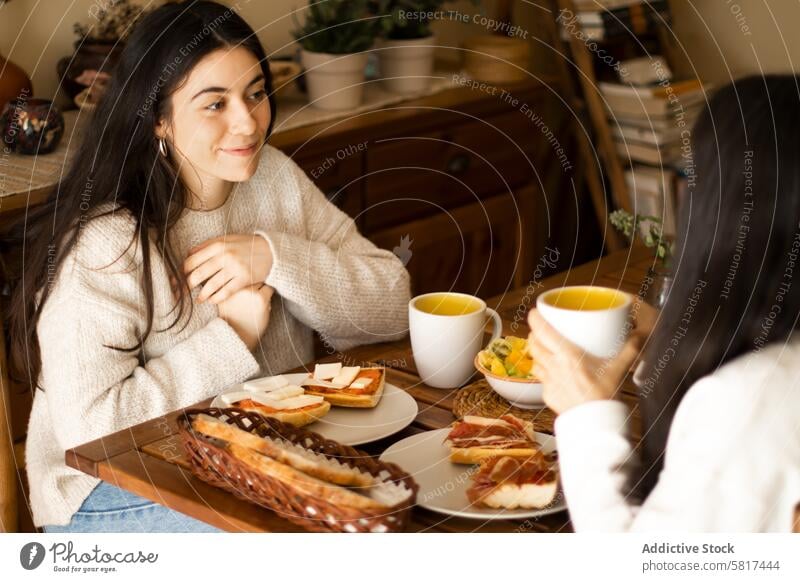 Beautiful young woman having breakfast with her mother. daughter family adult home happy caucasian girl smiling food people female morning parent kitchen