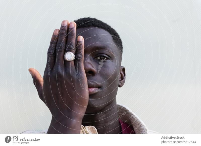 Stylish black man covering face and looking at camera cover face style hide handsome appearance serious trendy confident male ethnic african american young