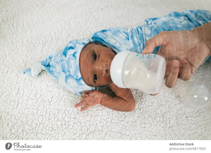 Anonymous mother feeding newborn baby wrapped on soft blanket little child sweet kid infant cute care adorable boy childhood lying innocent peaceful relax calm