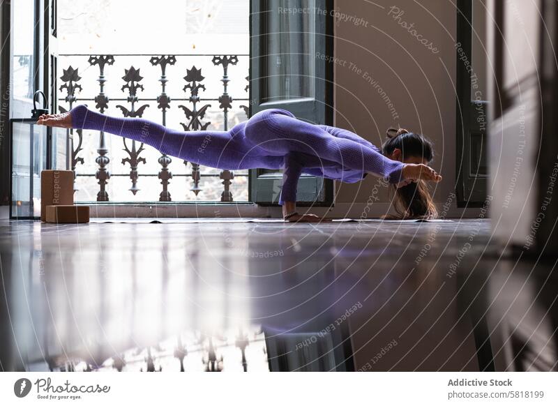 Fit woman doing Eka Pada Koundinyasana yoga pose on mat at home eka pada koundinyasana flying man flexible wellness stress relief mindfulness stretch wellbeing