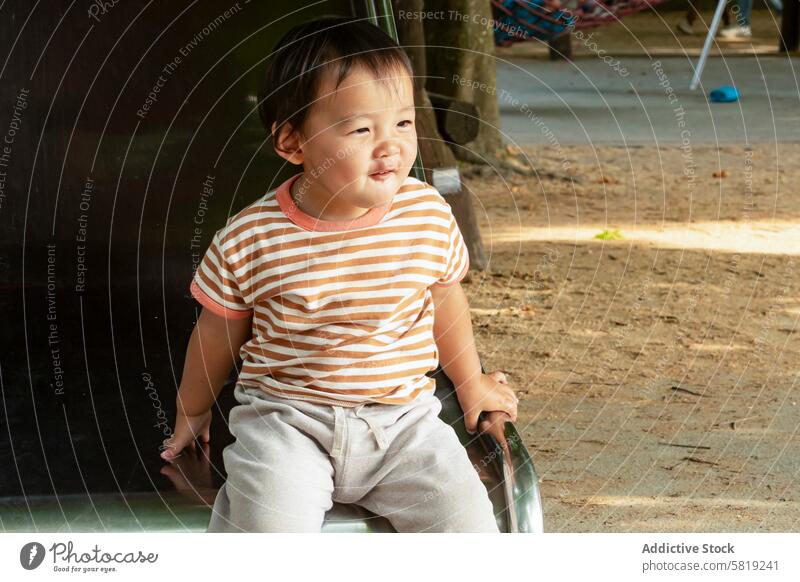 Toddler enjoying a sunny park during family trip toddler asian vacation europe child smile travel sunlight summer casual wear stripe t-shirt outdoor leisure