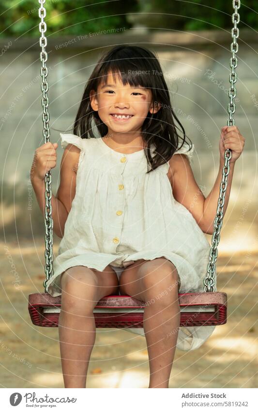 Joyful Asian girl swinging in a park during family vacation asian trip europe sunny joyful child play outdoor leisure activity summer happy childhood fun