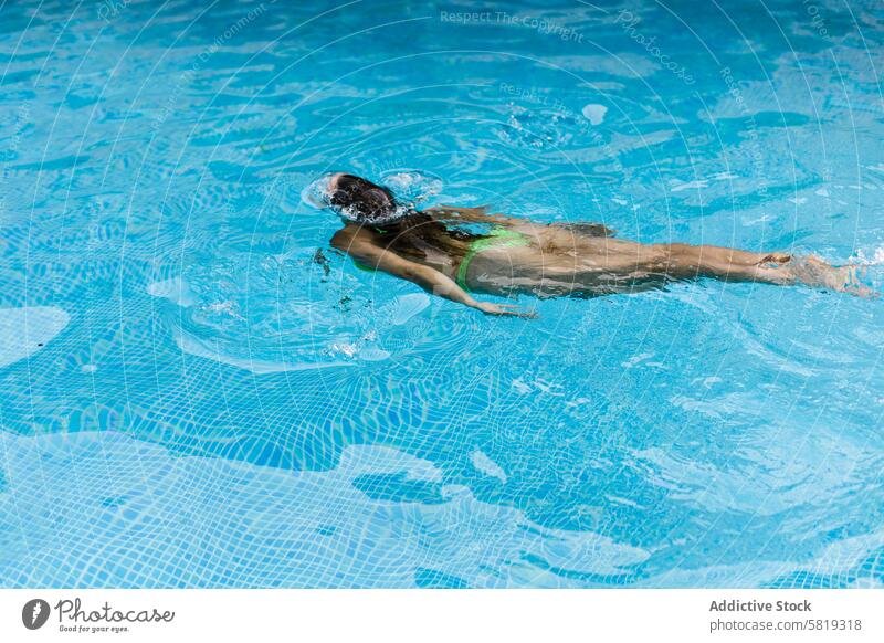 Young woman swimming freestyle in a clear blue pool swimmer water stroke fitness sport technique summer outdoor aquatic exercise healthy lifestyle female young