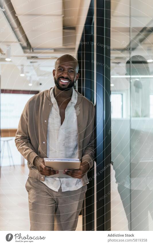 Smiling businessman at coworking space with tablet office casual modern bald holding digital professional ethnic attire cheerful male black technology workspace