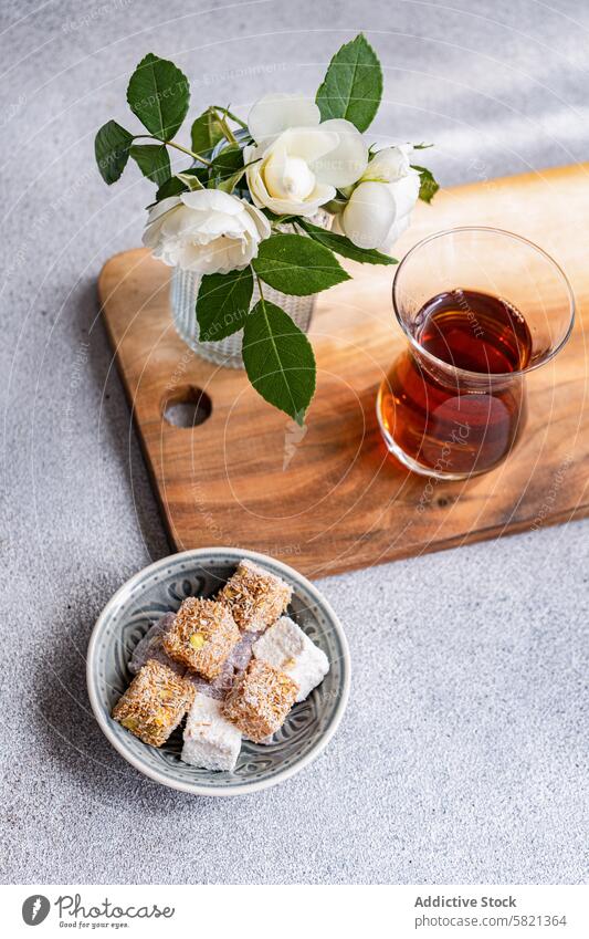 Turkish Delights and Tea with White Roses Decor turkish delights black tea glass vase white roses wooden board plate assorted mix snack sweet traditional treat