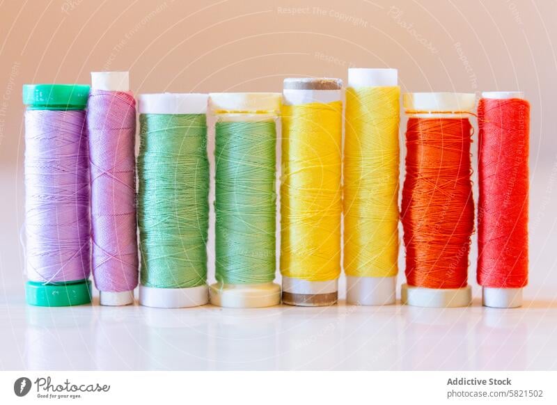 Colorful Sewing Thread Spools on a Table thread spool sewing colorful textile equipment craft material cotton polyester purple green yellow red fashion design