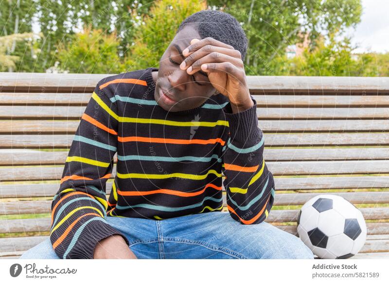 Young man feeling dizzy after soccer game young dizziness ball bench park hypoglycemia symptom weary tired sport activity physical exhaustion health issue