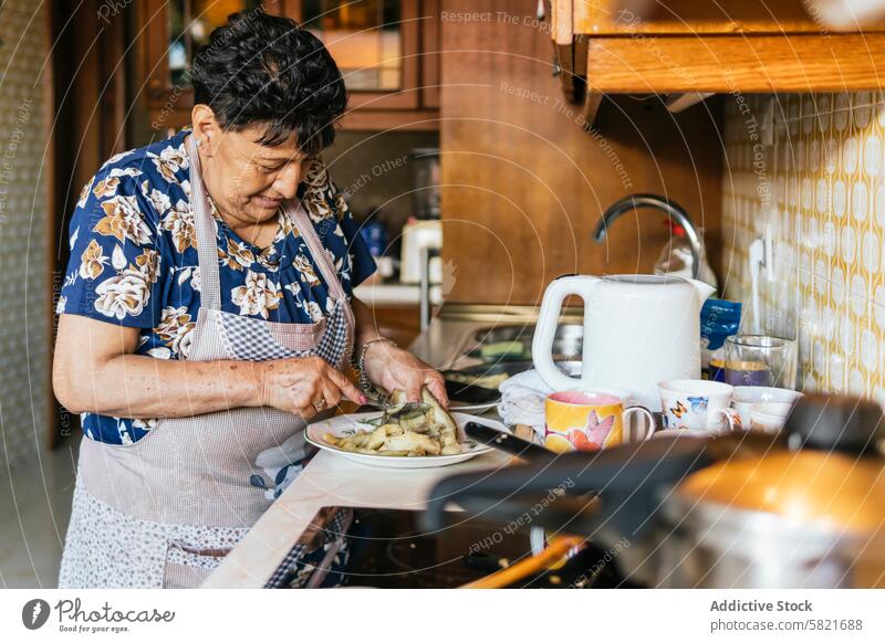 Senior Woman Preparing a Meal in Her Kitchen senior woman cooking home kitchen elderly food preparation homely domestic interior meal apron preparing female