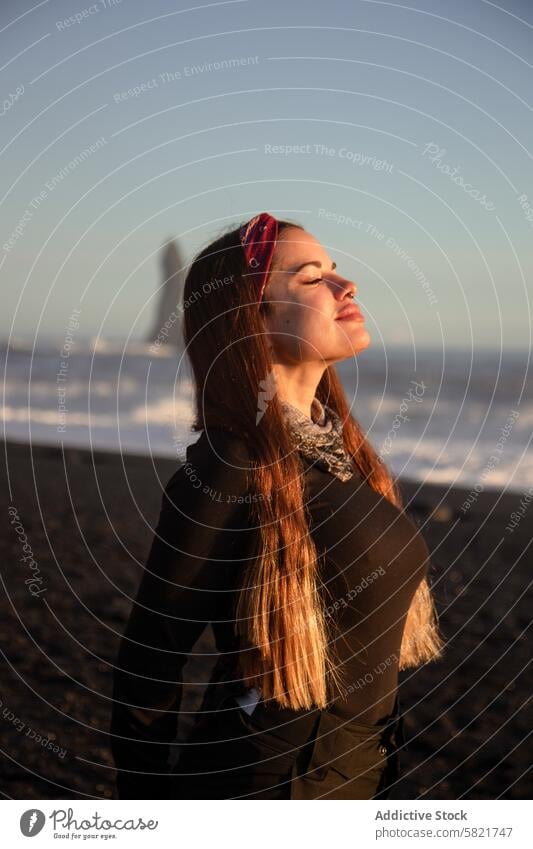 Woman enjoying the serenity of a black sand beach in Iceland woman iceland sunlight ocean wave volcanic travel outdoor nature scenic rock sea landscape beauty