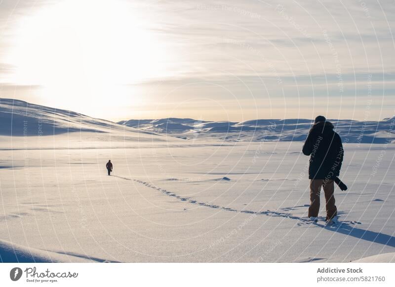 Tranquil snowy landscape in Iceland with two explorers iceland winter solitude sky bright serene vast footsteps trail cold nature outdoor scenic travel