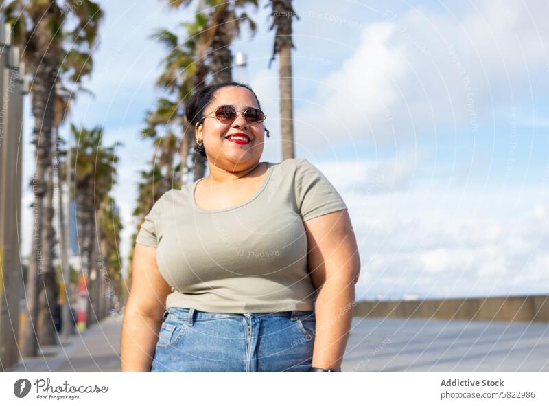 Smiling Woman Enjoying a Sunny Day in Barcelona woman smiling summer barcelona promenade palm tree sunny stroll friends happy cheerful sunshine african american