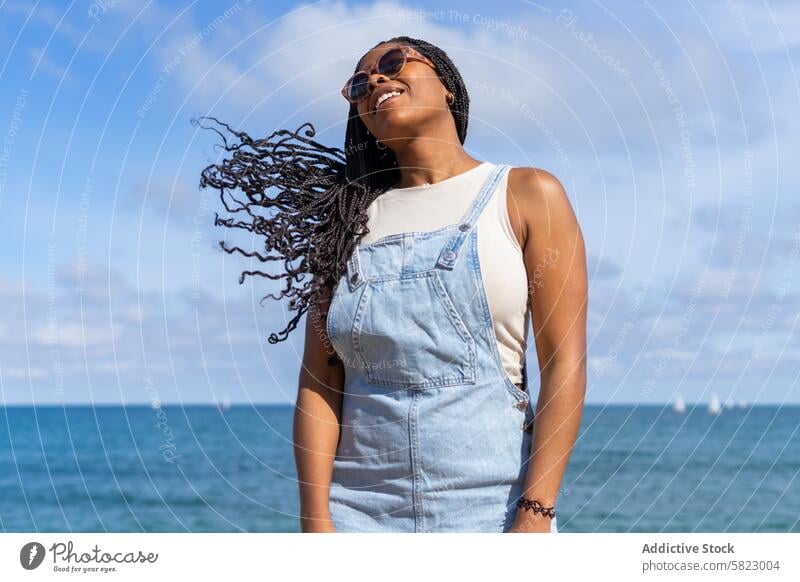 Joyful young woman enjoying summer in Barcelona smile happy barcelona sea sunny denim overalls happiness beach vacation holiday sky ocean waterfront trendy