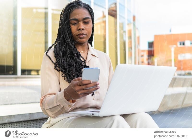 Businesswoman multitasking with phone and laptop outdoors businesswoman smartphone working seated sunny day city barcelona summer friends technology mobile