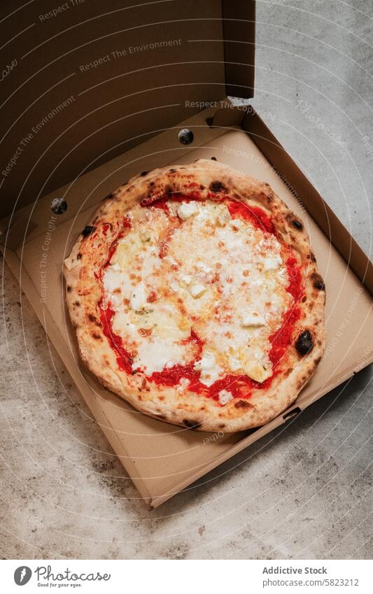 Fresh pizza in a box on a concrete surface takeaway delivery pizzeria food meal cheese tomato dough baked crust cardboard overhead view fresh hot lunch dinner