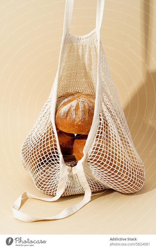 Sourdough breads in a reusable mesh bag on a beige background sourdough baked bakery eco-friendly fresh artisan crusty loaf homemade natural flour