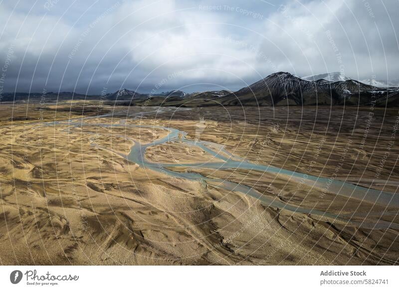 Meandering river through volcanic highlands landscape aerial texture barren serpentine meandering snow-capped peak distant nature view earth erosion sediment