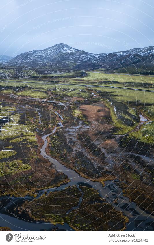 Serene aerial highlands with meandering river and snowy peaks mountain landscape nature serene vast view grey sky background riverbed water flow stream