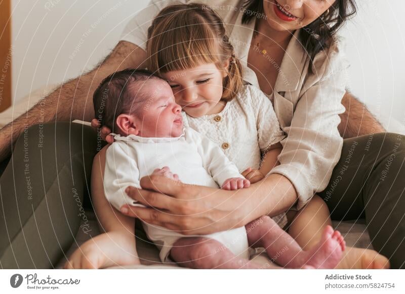 Family welcoming a newborn baby at home family sibling love tender warmth holding child affection care comfort togetherness parent mother father daughter