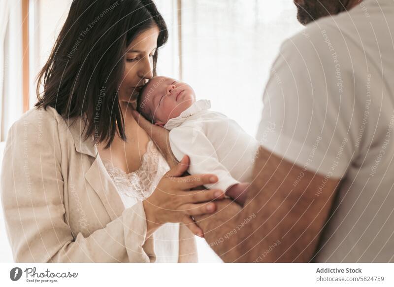 Newborn embraced by parents in a gentle moment mother father newborn baby kiss sleeping love family tender care holding affection bond infant child soft warmth