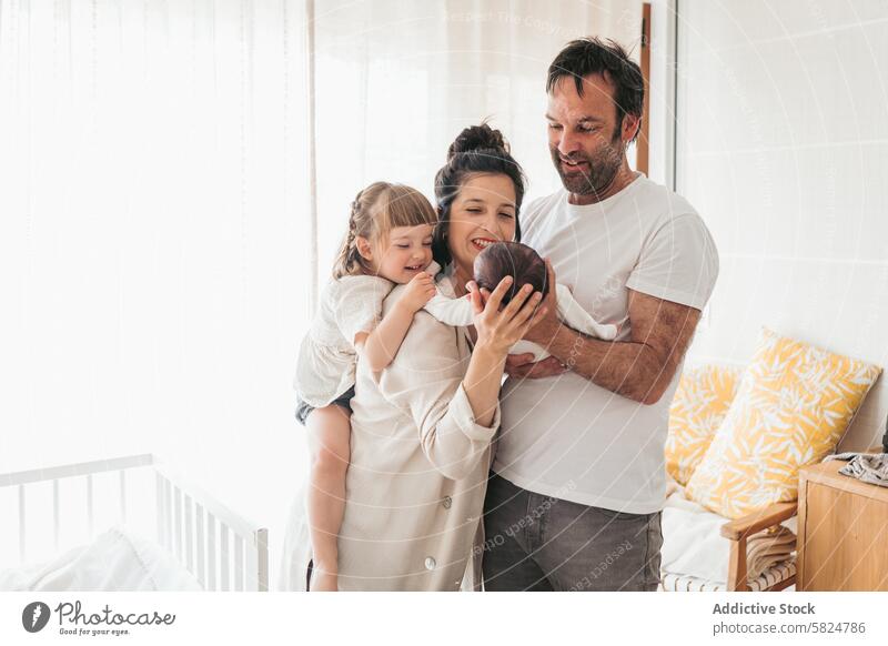 Joyful Family Embracing Newborn at Home family newborn baby embrace tender moment older sibling admire home indoor affection happiness love togetherness parent