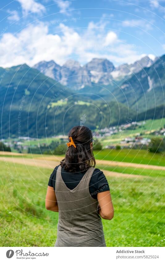 Woman gazing at the majestic Italian and Austrian Alps woman alps italian austrian mountain view panoramic nature travel landscape blue sky cloud lush field