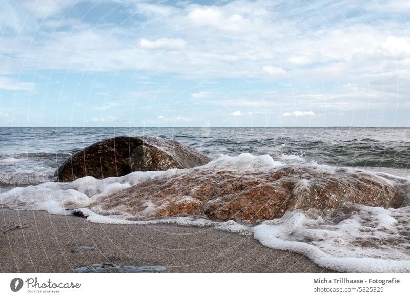 Stones washed by water in the sea Ocean Baltic Sea stones rock Water Waves White crest Foam Sand Beach Horizon Landscape Nature Sky Clouds Sun sunshine Deserted