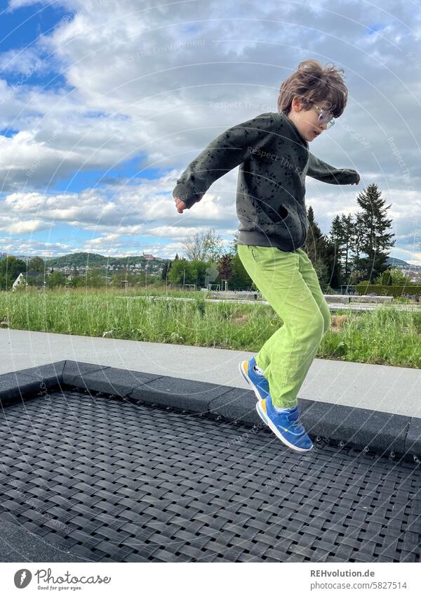 Boy jumps on a trampoline Playground Movement Jump Authentic Park Nature Environment Child Boy (child) Infancy Sports Training Fitness Dynamics Human being