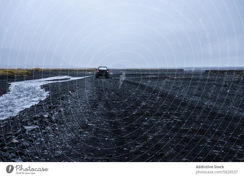 Solitary vehicle on a rugged road in the Iceland Highlands iceland highlands travel gravel desolate landscape moody cloudy sky snowflake car lone solitary