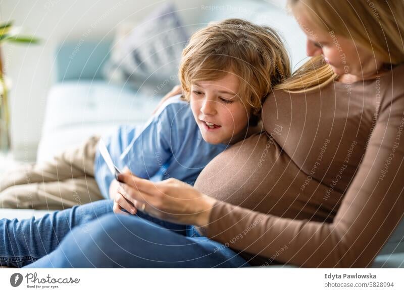 Little boy with his pregnant mother at home pregnancy adult anticipation awaiting baby belly birth body care caucasian child expectant expecting expectation