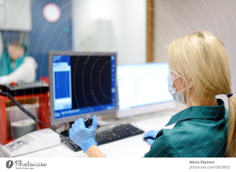 Female radiologist is going to take X ray of patient in X-ray room of modern clinic. Close up photo of doctor hand presses button for execute of medical examination