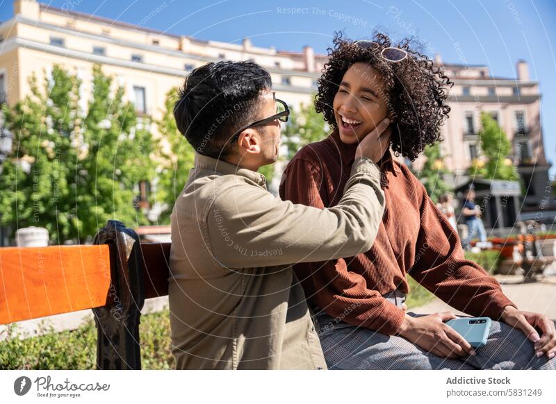 Multiethnic couple enjoying a sunny day together in Madrid multiethnic chinese hispanic man woman madrid spain bench outdoor park smile love affection happiness