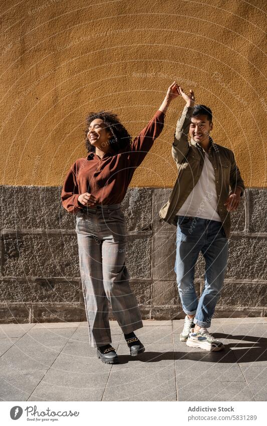 Joyful multiethnic couple dancing on the streets of Madrid dance joy happiness urban city madrid spain multicultural chinese hispanic love relationship fun