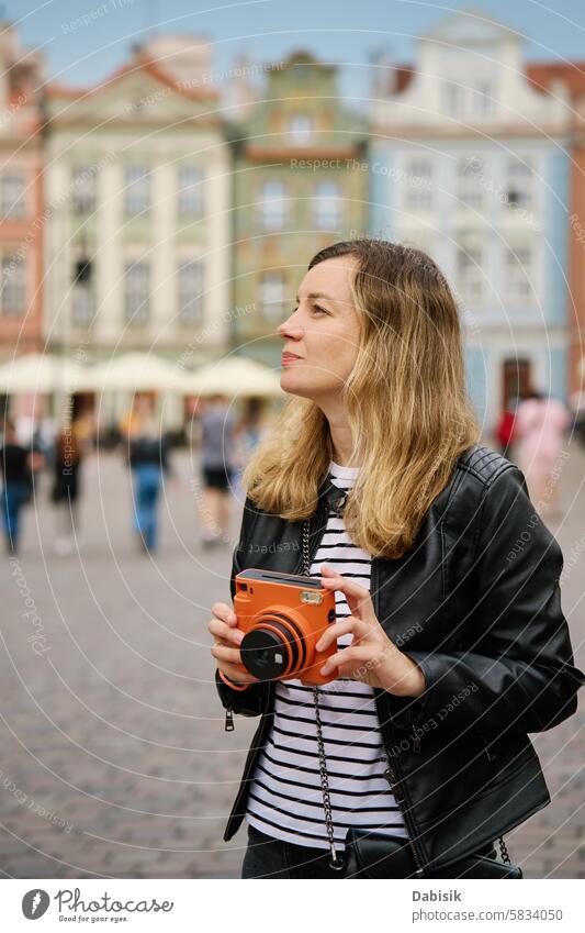 Female traveler taking picture with vintage instant camera tourist photo woman tourism photography memories trip scenic daytime capture orange retro nostalgia