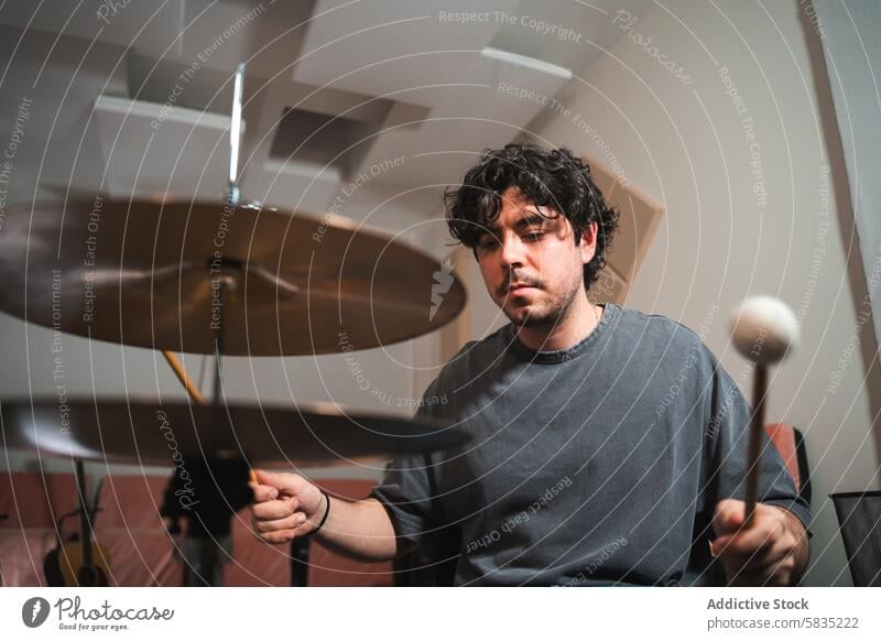 Young male drummer playing in a home studio setup musician cymbal young talent practice instrument performance casual focus concentration chair session art