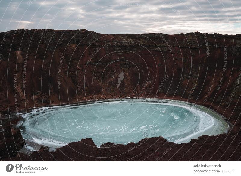 Overlooking a Frozen Crater Lake in Iceland's Rugged Landscape iceland crater lake frozen snaefellsnes peninsula landscape moody sky red rock isolation beauty