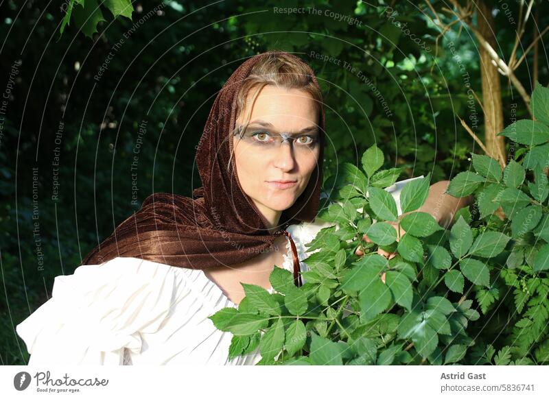 A woman, dressed as a medieval huntress, looks out of the forest Woman Witch Elf enchantress magician Face Cape elfin witchy fantasy Slayer Hunting hunting Hand