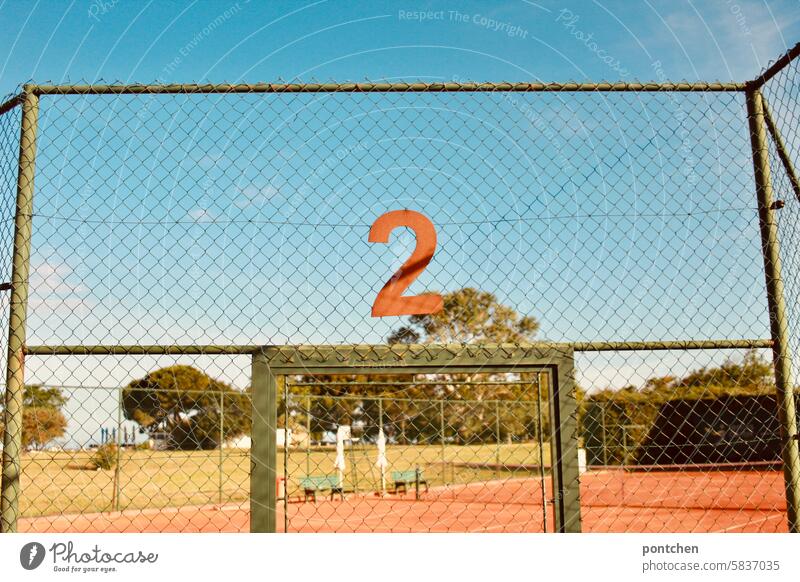 A rusty 2 hangs above the entrance to a tennis court. Tennis Tennis court two number Numbering Sports facility demarcation Ball sports Leisure and hobbies Goal