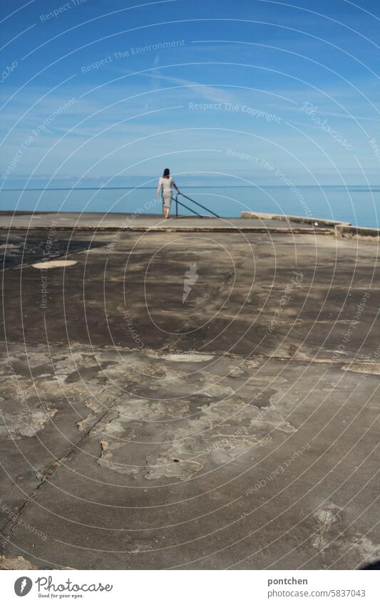 a woman walks over a concrete slab towards the sea and a staircase into the water . rear view Ocean vacation holidays Happiness Caucasian Life Woman Back