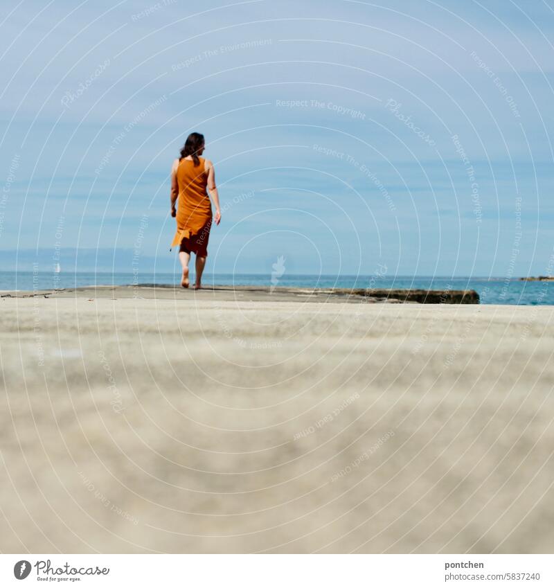 woman walks along a jetty by the sea. rear view Ocean vacation Footbridge holidays Dress Happiness Caucasian Life Woman Back from behind snorkel Diving goggles