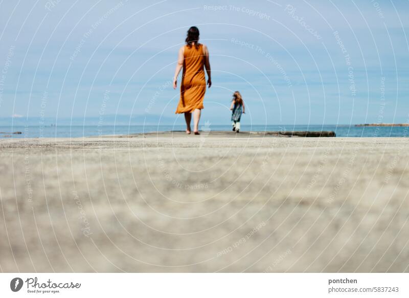 Mother and child walk one behind the other along a jetty by the sea. growing up, cutting the cord. Child Love Happy Together Family & Relations