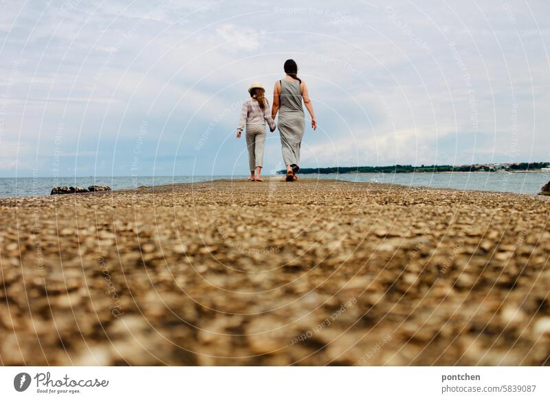 Mother and child walk hand in hand along a jetty by the sea. Child Love Hold hands Happy Together Family & Relations Feeling of togetherness Mother with child