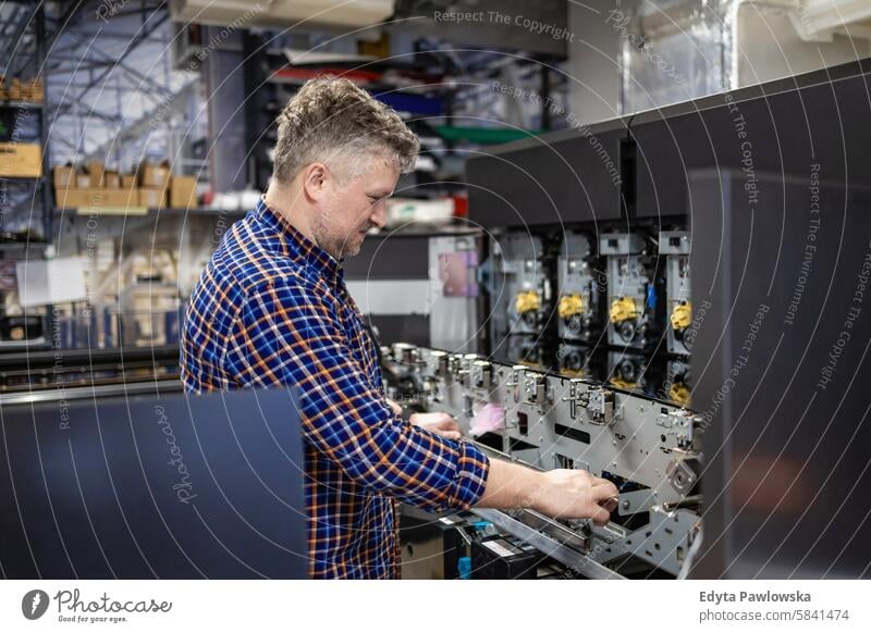 Maintenance engineer in a in printing house fixing machine repairing technician skilled machinery electronics industry mechanical engineering examining workshop