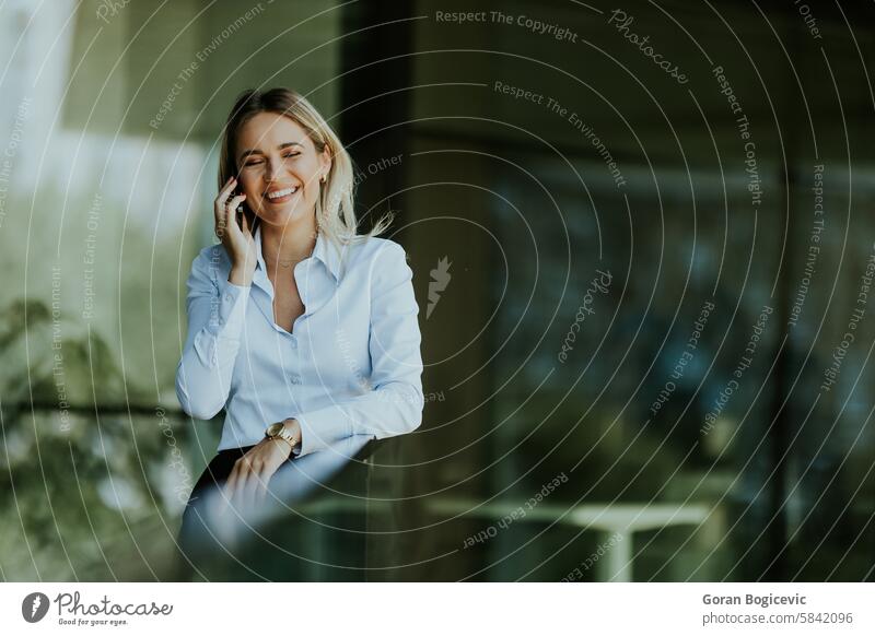 Young professional woman talking on a phone call outdoors on a sunny day businesswoman smiling conversation work mobile communication attire urban white blouse