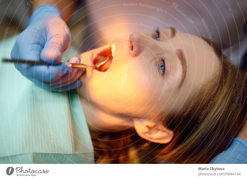 Dentist and patient at modern medical center. Doctor treats a young woman teeth in hospital. Practitioner examines the patient before orthodontists or prosthetics treatment.