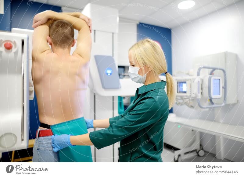 Female radiologist is going to take an Xray of patient in X-ray room of modern clinic. Doctor prepares patient for fluorography. Medical examination of people is prevention of tuberculosis spread