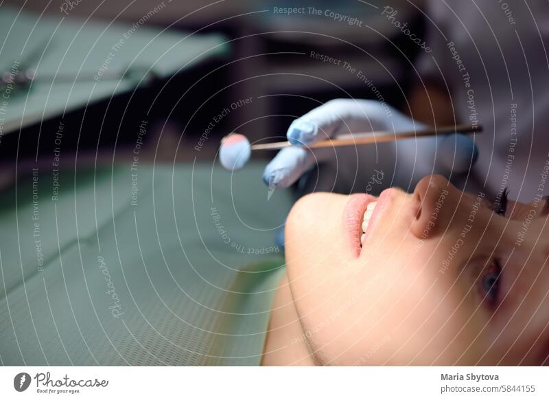 Dentist and patient at modern medical center. Doctor treats a young woman teeth in hospital. Practitioner examines the patient before orthodontists or prosthetics treatment.