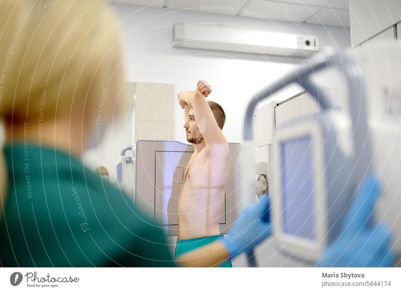 Female radiologist is making an Xray of lungs of patient in X-ray room of modern clinic. Doctor performs a fluorography. Medical examination of people is prevention of tuberculosis spread