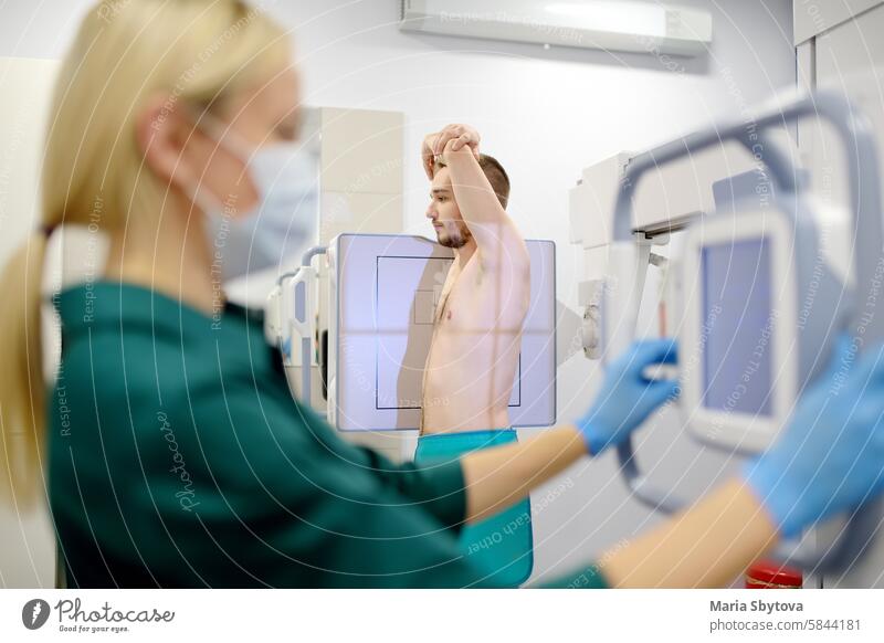 Female radiologist is making an Xray of lungs of patient in X-ray room of modern clinic. Doctor performs a fluorography. Medical examination of people is prevention of tuberculosis spread