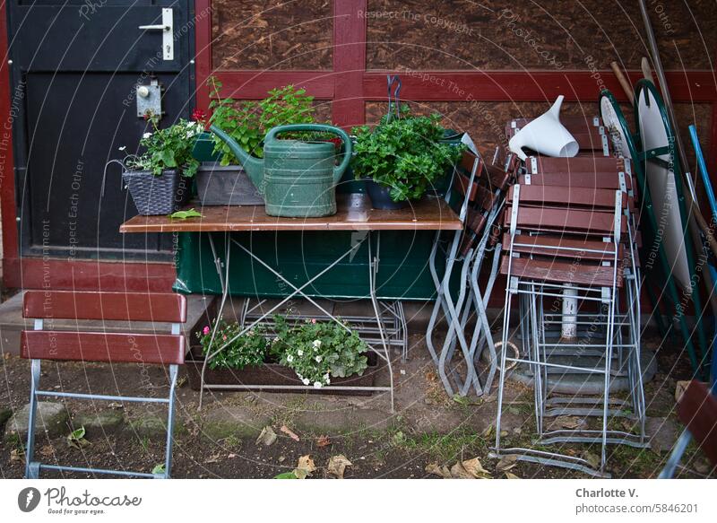 UT Leipzig - cheerful to cloudy I Orderly chaos with folding chairs, plants, watering can and table on a hut wall havoc orderly chaos Folding chairs