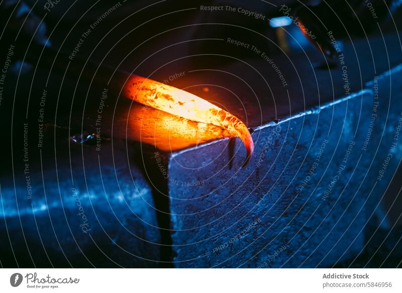 Glowing hot metal on anvil in blacksmith's workshop glowing rod bent heated sparks dimly lit close-up craftsmanship forging iron tool orange hammer traditional